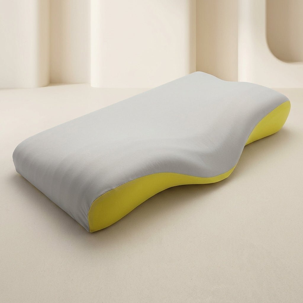 A contoured ergonomic pillow with a light gray fabric cover and a bright yellow underside, shown on a minimalist beige background.