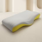 A contoured ergonomic pillow with a light gray fabric cover and a bright yellow underside, shown on a minimalist beige background.