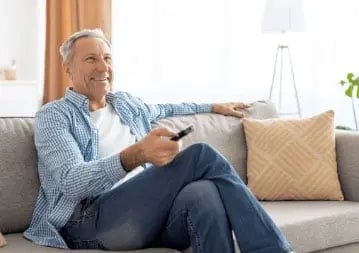 Man on a sofa holding a TV remote