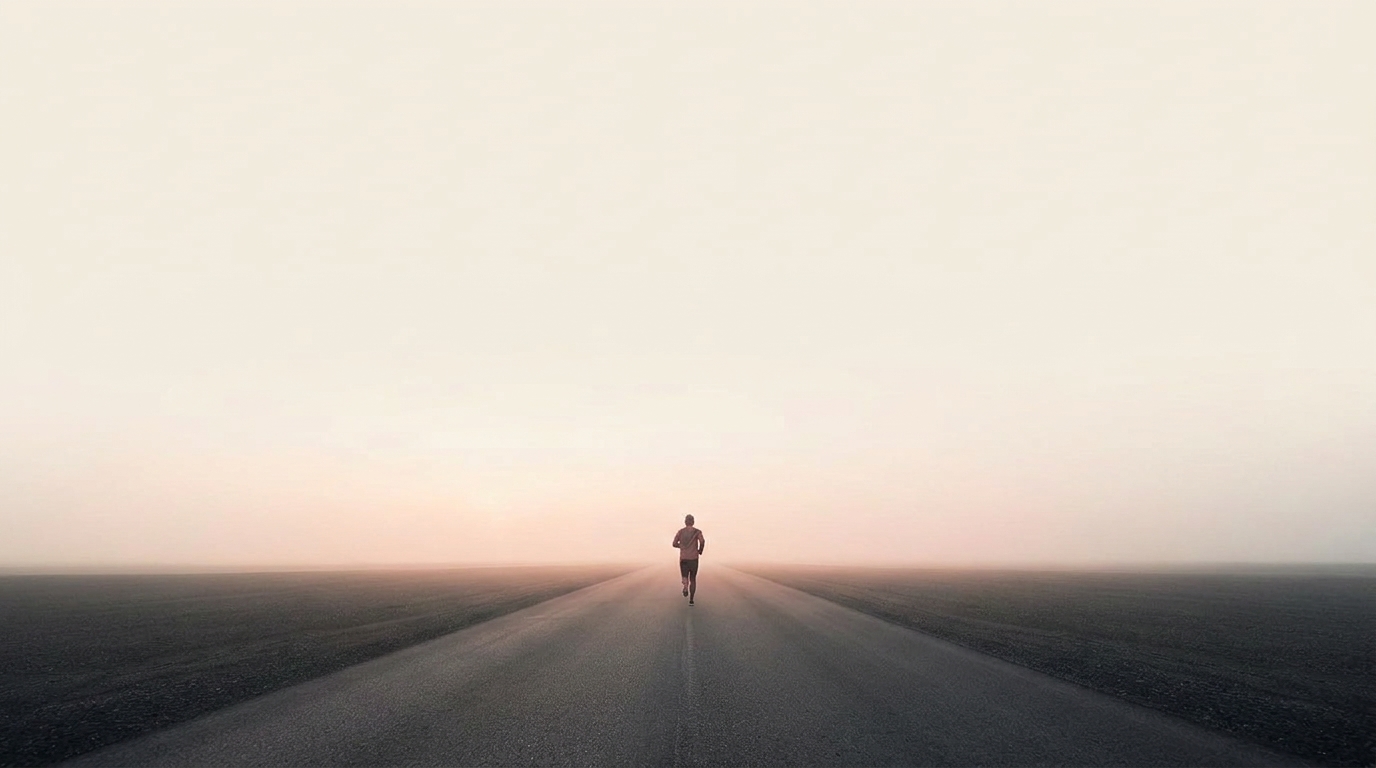 A runner on an empty dawn road in a graphite training shirt