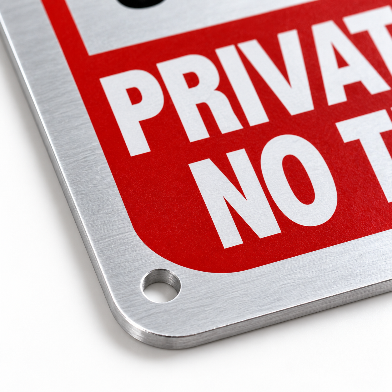 Close-up of the warning sign's pre-drilled corner hole and brushed metal edge