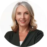 A woman with blonde hair smiling, wearing a dark jacket, against a white background.