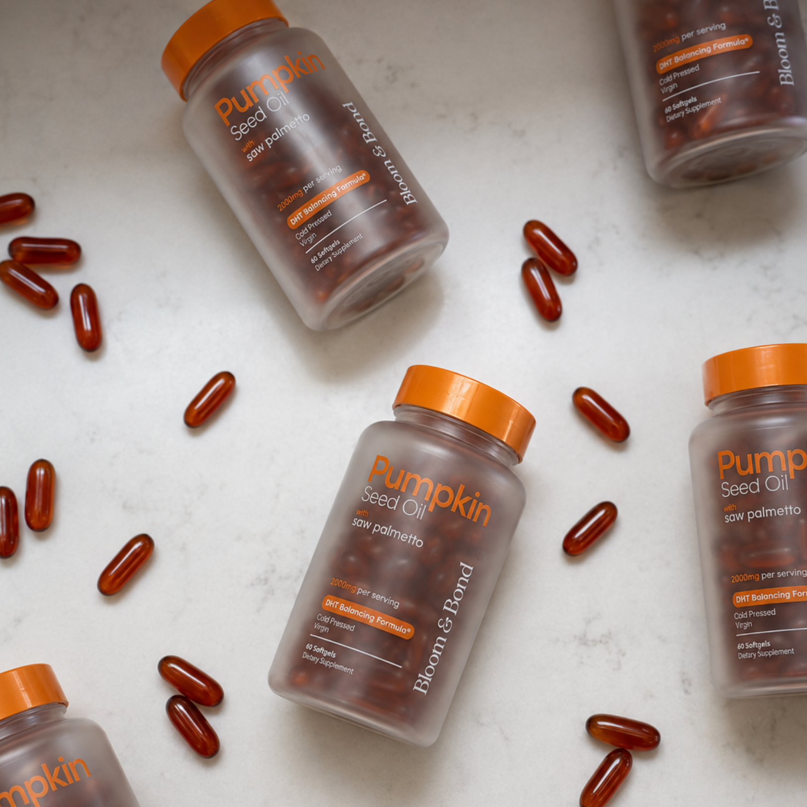 A flat lay of pumpkin seed oil supplement bottles and softgels scattered on a white surface.