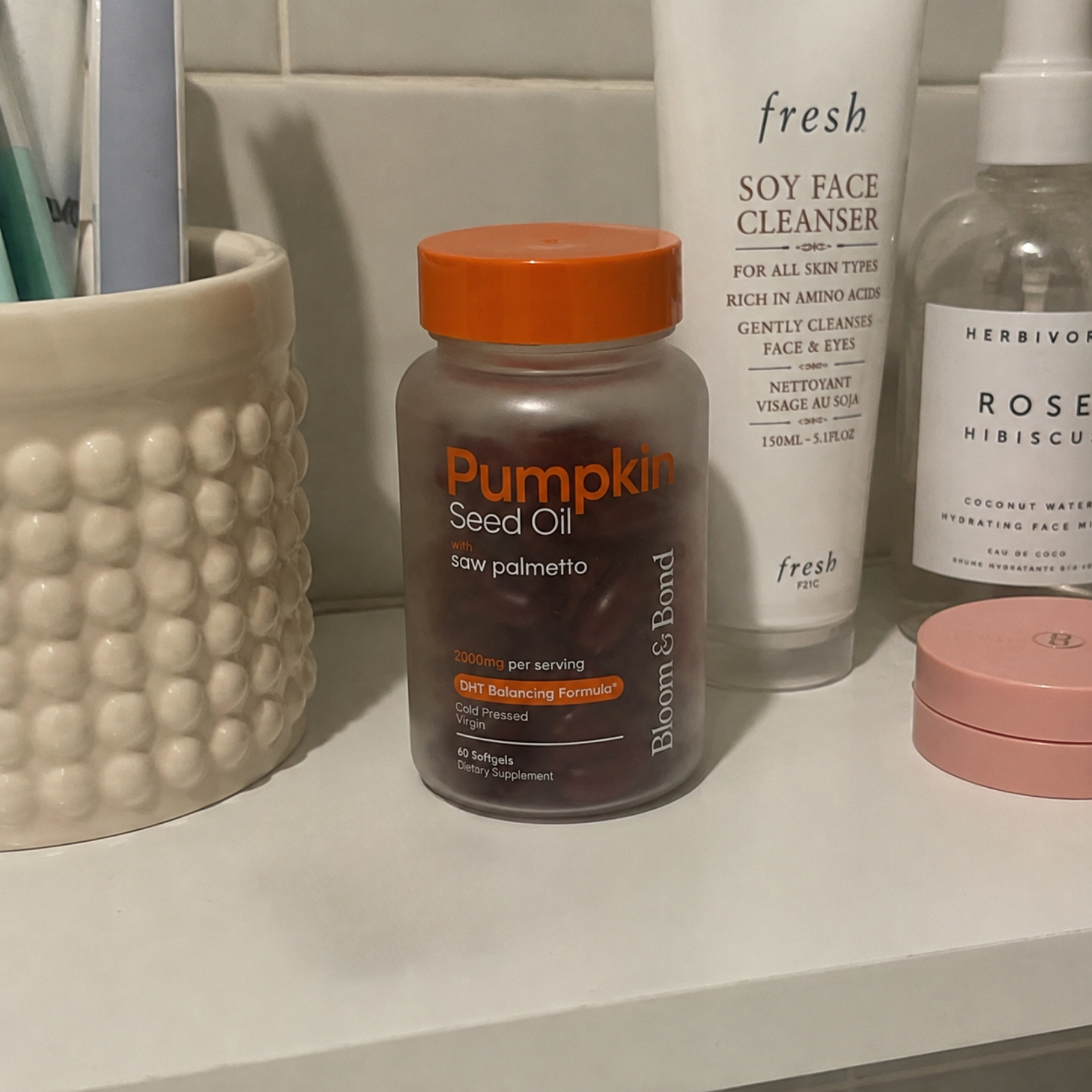 A bottle of Pumpkin Seed Oil supplements sits on a bathroom counter next to other skincare products.