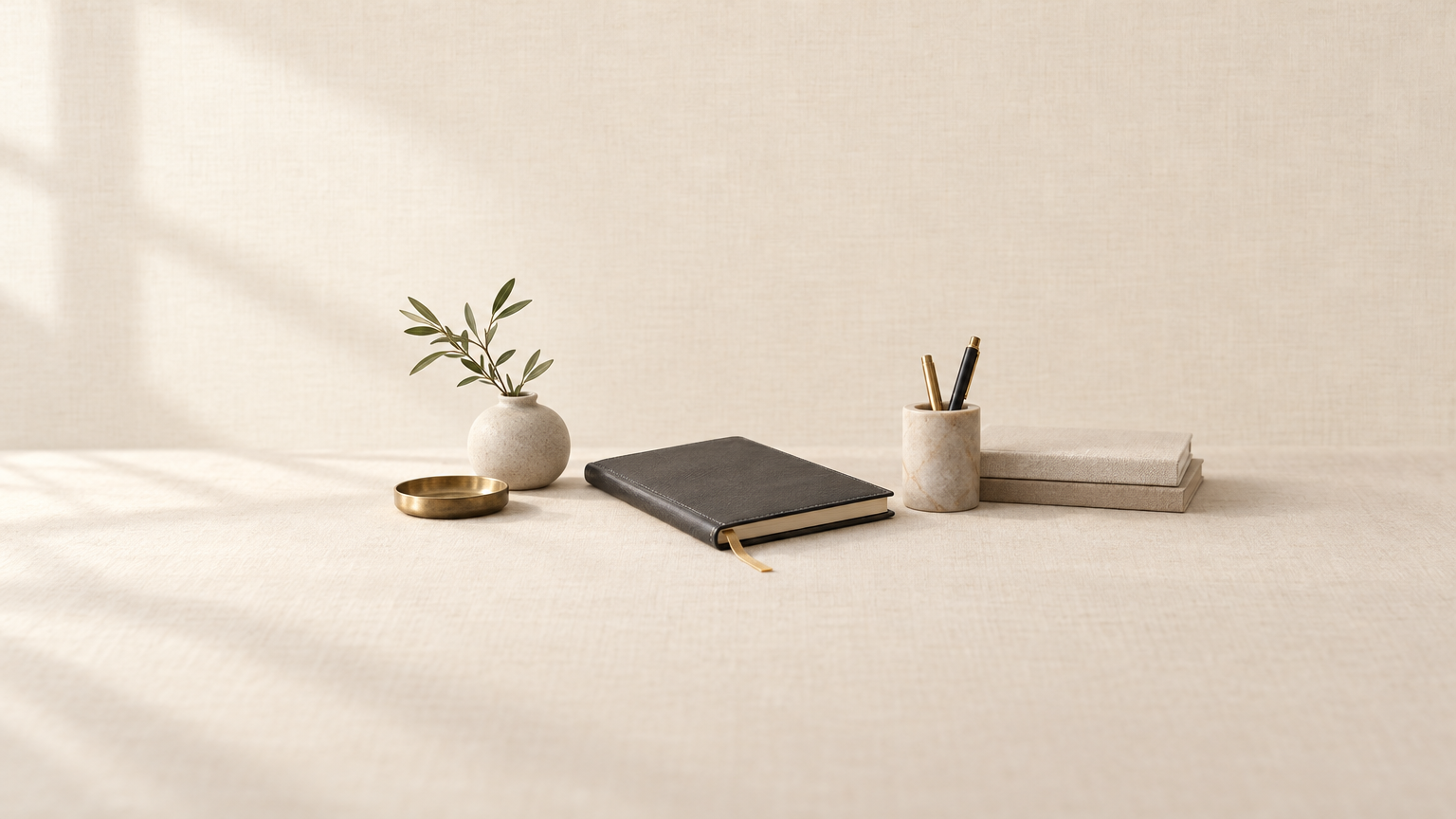 A linen desk with paper, brass, and a folded Vellum mark