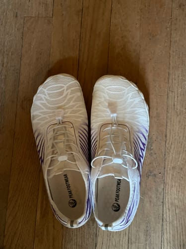 Customer's white and purple Lorax Pro barefoot shoes seen from above on a wooden floor.