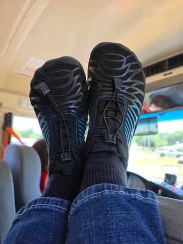 Customer's feet propped up, showing off their black Lorax Pro barefoot shoes with blue accents.