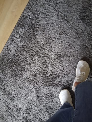 Reviewer standing in white Lorax Pro barefoot shoes on a shaggy grey rug.
