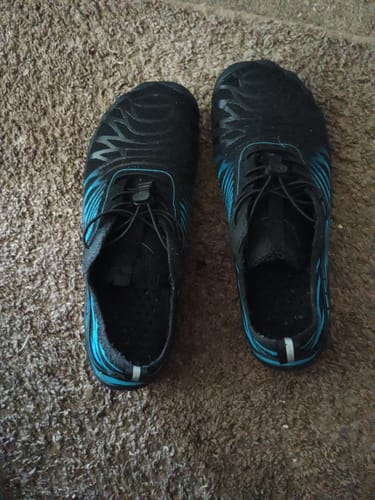Reviewer's pair of black Massage Insole shoes with blue patterns, shown from above on a carpeted floor.