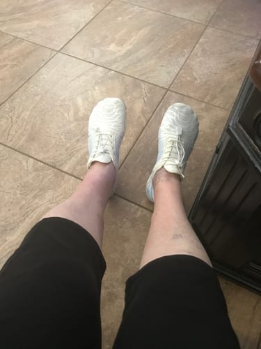Reviewer's perspective looking down at their feet in the white, wide UniGrip shoes.