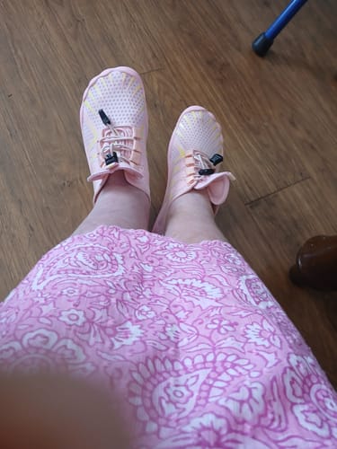Customer's feet wearing pink Lorax Pro Winter barefoot shoes, paired with a patterned pink skirt.