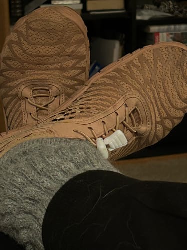 Customer relaxing with their feet up, wearing tan UniGrip traction shoes and showing the detailed sole.