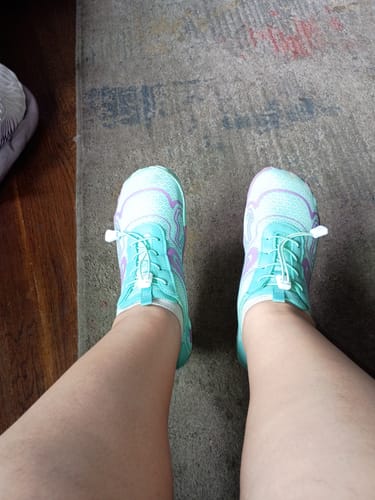Reviewer's first-person view of their turquoise and purple Lorax Pro barefoot shoes.