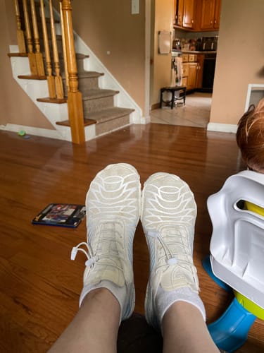 Customer's feet wearing off-white Lorax Pro barefoot shoes while sitting at home