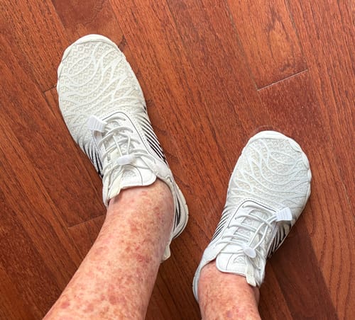 Customer's Lorax Pro barefoot shoes in white, worn on feet while standing on a wood floor.