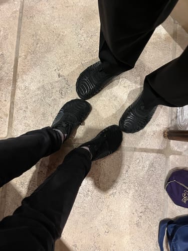 Customer's Lorax Pro black barefoot shoes worn by two people standing on a tiled floor.