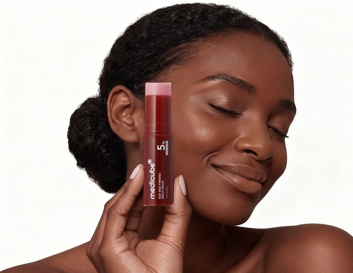Woman holding the medicube NAD+ EGF Firming Multi Balm beside her cheek