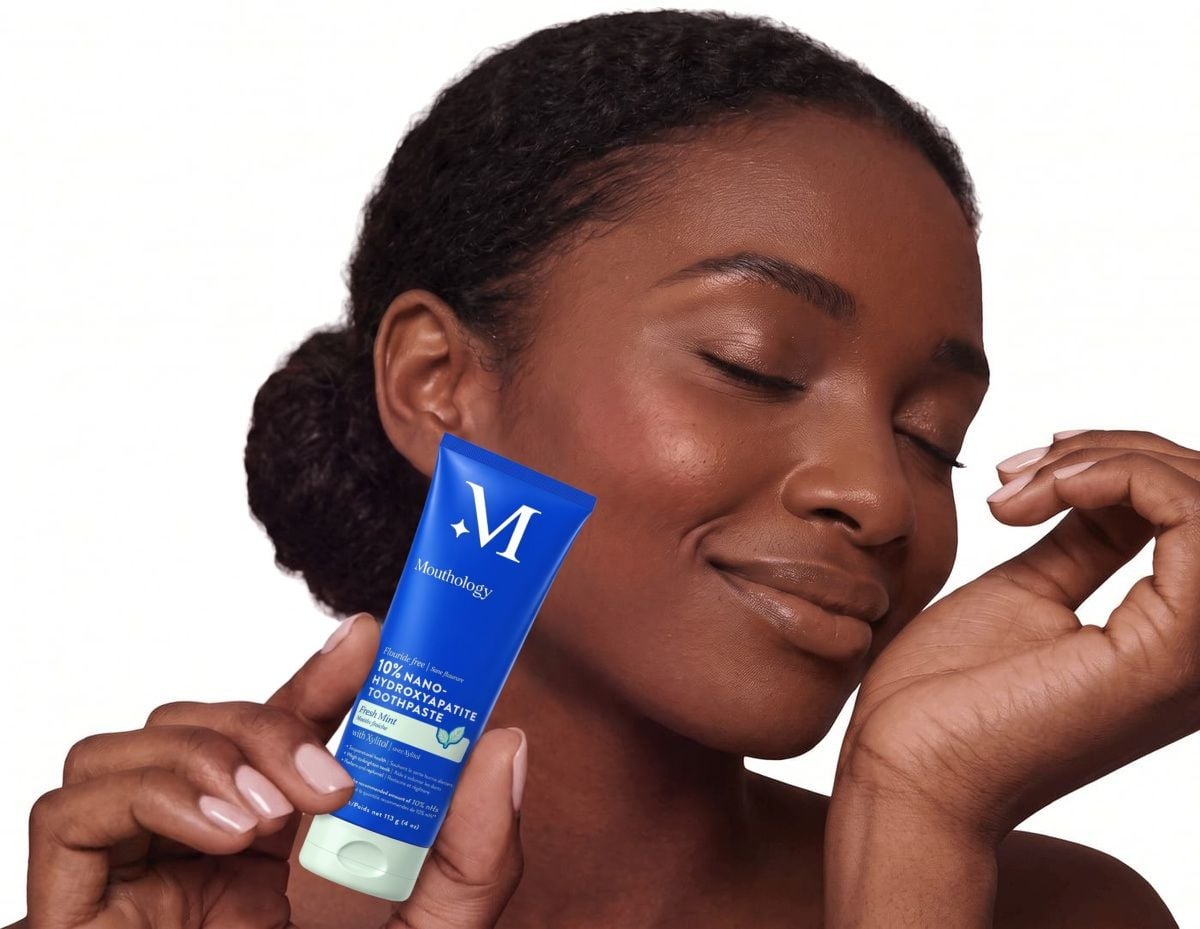 Woman holding the Mouthology 10% Nano-Hydroxyapatite Toothpaste beside her cheek