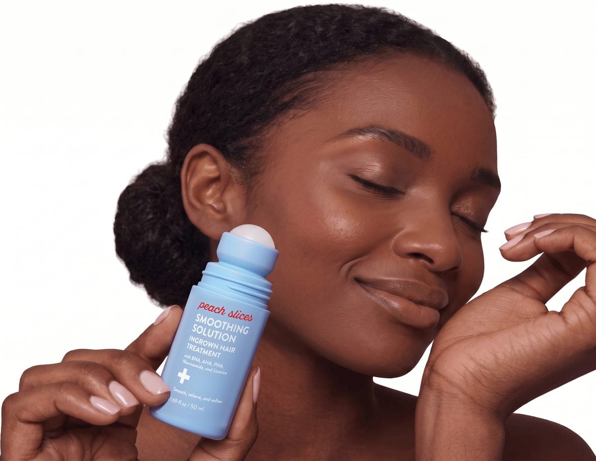 Woman holding the Peach Slices Smoothing Solution roll-on beside her cheek